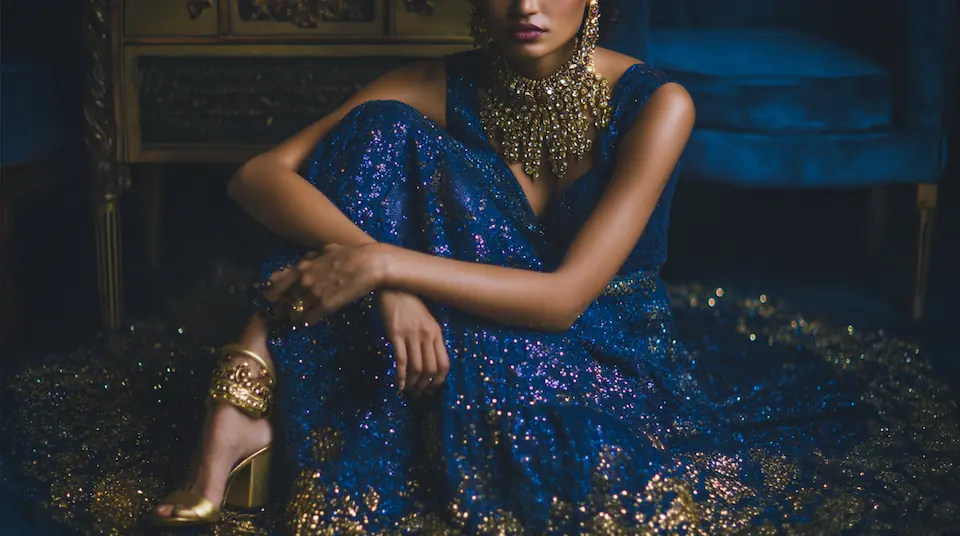 Sangeet night outfit flat lay with sequined blue lehenga, kundan necklace, gold heels, and beaded clutch
